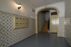 Classic hallway with patterned tile wall and wooden staircase.