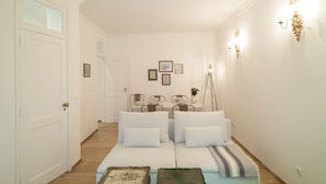 Un pasillo que conduce a un comedor con un sofá blanco y una mesa dispuesta para cuatro comensales.