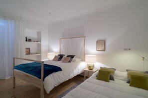 Relax in this serene bedroom with a large bed, sofa, and wall-mounted shelf.