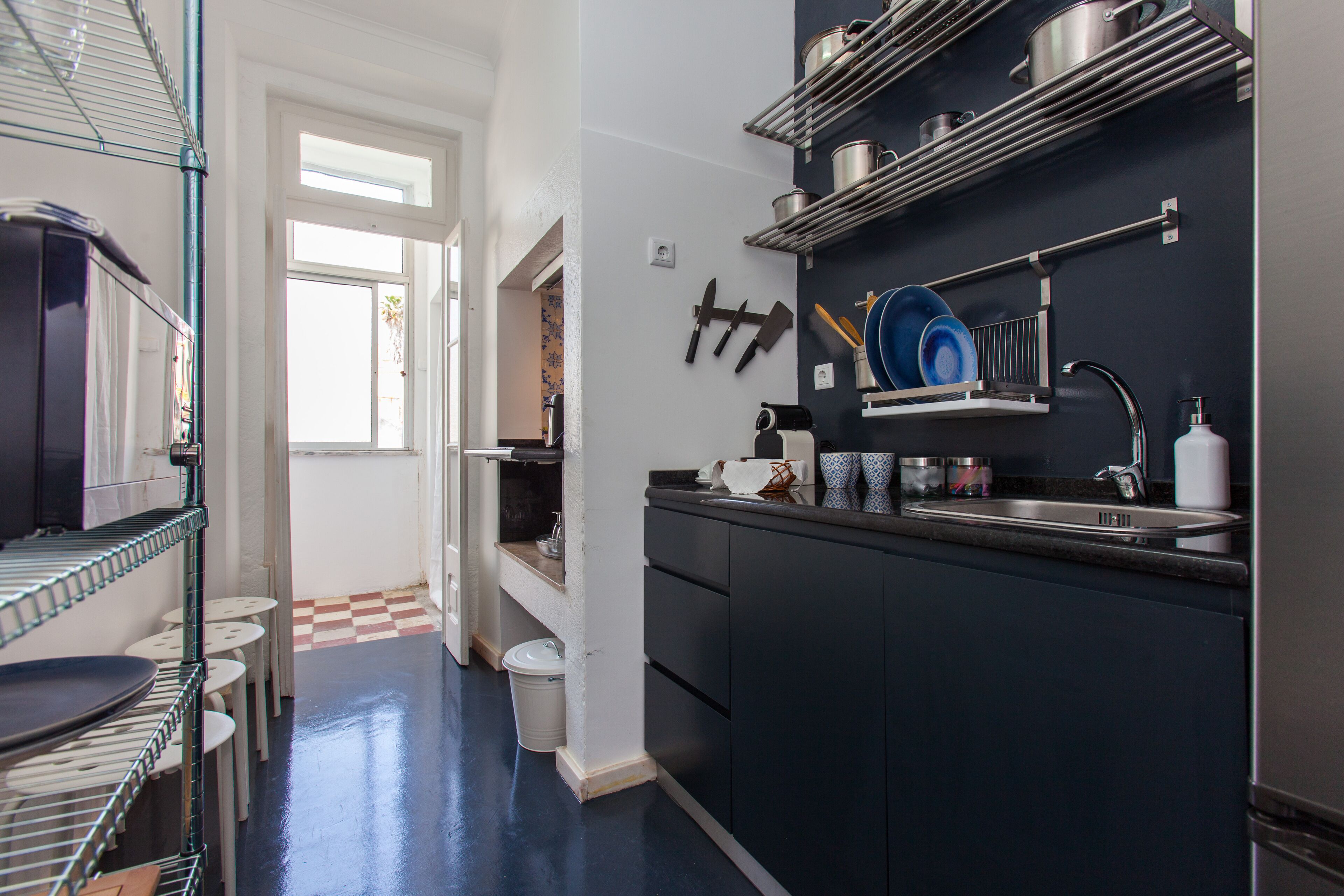Een moderne keuken met een zwart aanrecht, roestvrijstalen apparatuur en een raam dat voor natuurlijk licht zorgt.