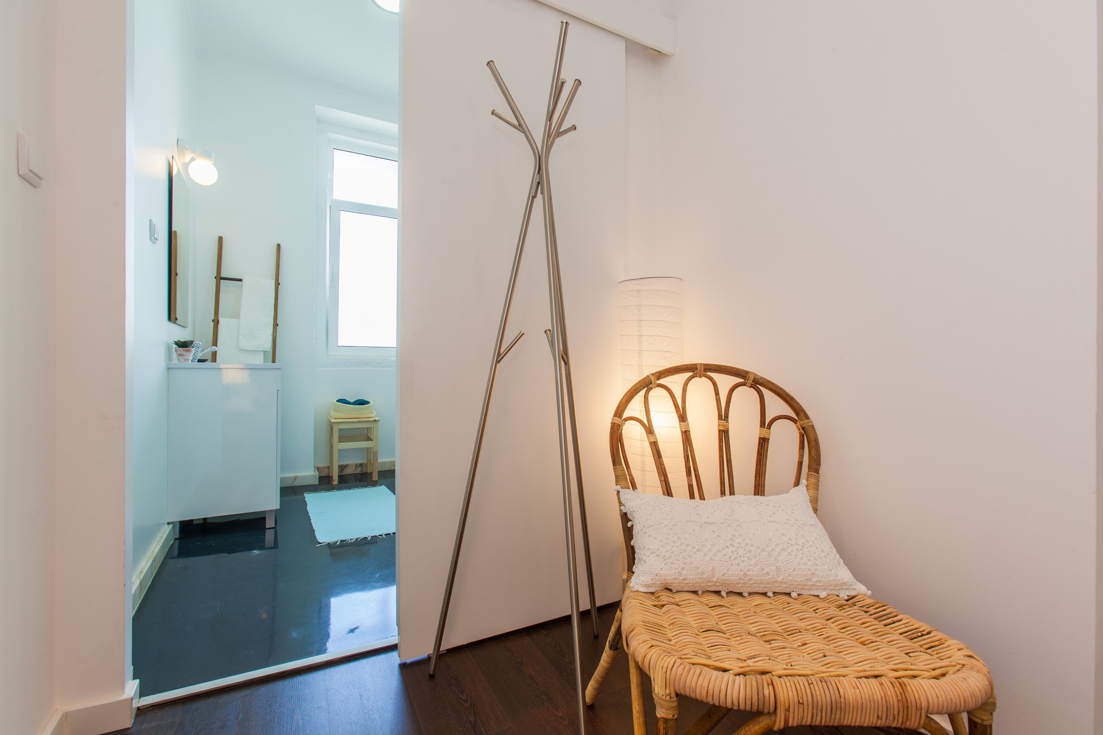 A room with a wicker chair, a floor lamp, and a mirror on the wall.