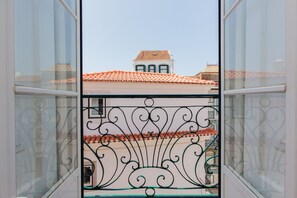 A balcony with ornate metal railings and a view of a building with a tiled roof. - Alfama Sunny & Typical Apartment, By TimeCooler (Lisbon)