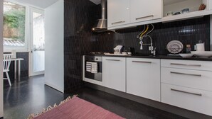 A modern kitchen with white cabinets, a black tiled backsplash, and a stainless steel range hood. - Renovated Apartment w/ Private Courtyard, By TimeCooler (Lisbon)
