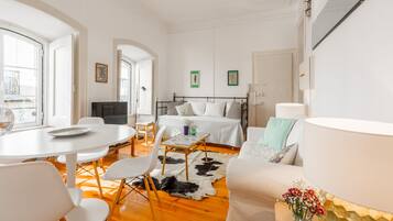 A modern, well-lit room with a bed, a dining table, and a sofa.