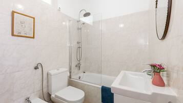 A bathroom with a toilet, bidet, bathtub, and sink.