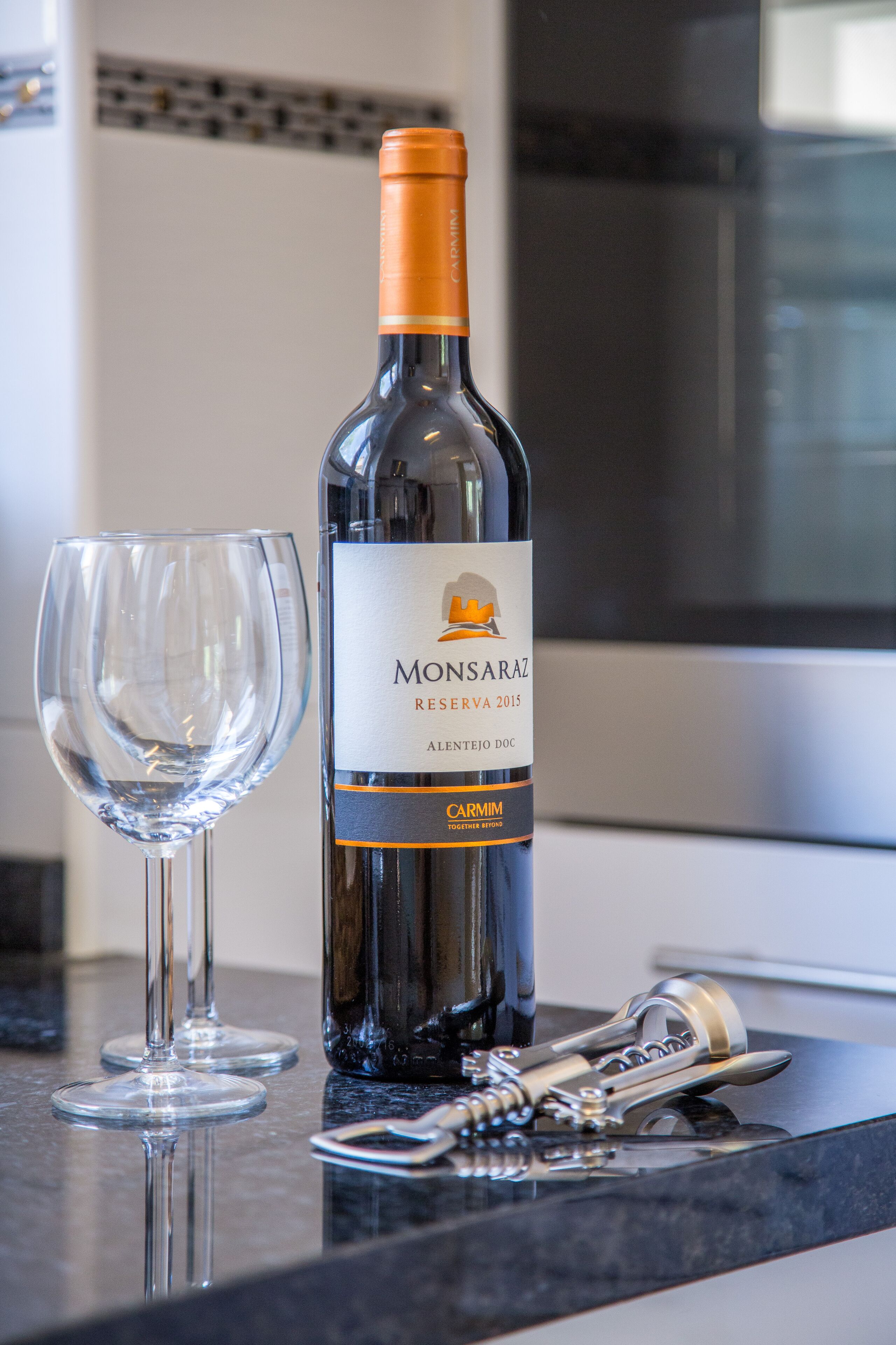 A bottle of wine and a glass on a kitchen counter.