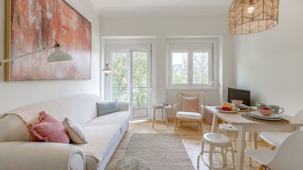Ett modernt vardagsrum med en stor, abstrakt målning, en vit soffa, ett matbord med stolar och en hängande lampa.