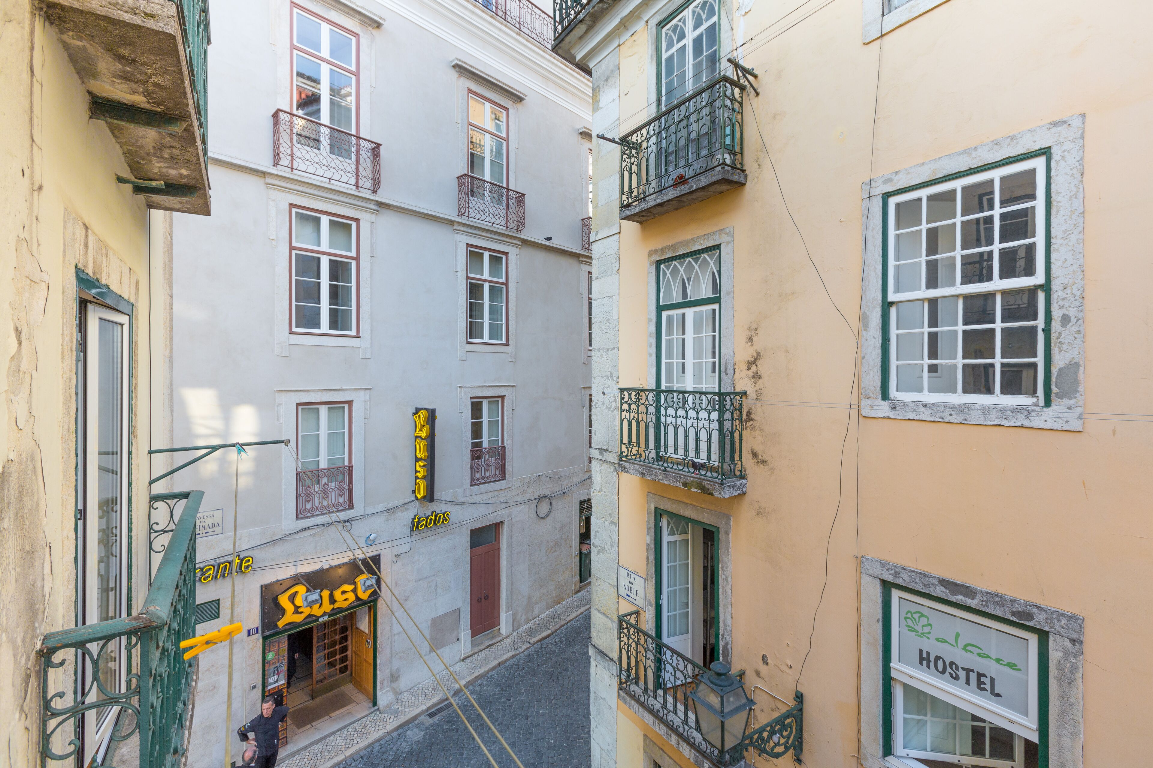 Une rue étroite bordée d’immeubles dotés de balcons, avec une enseigne indiquant la présence d’une auberge de jeunesse.