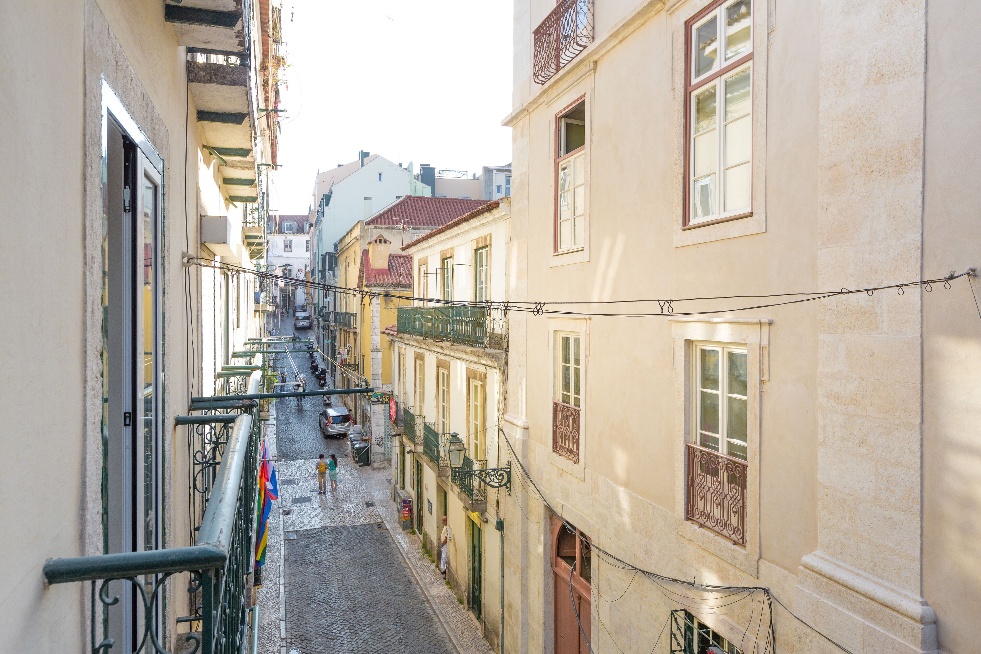 A narrow cobblestone street flanked by buildings with balconies and windows.