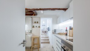 Una cocina moderna con armarios blancos, un taburete de madera, un microondas y una estufa.