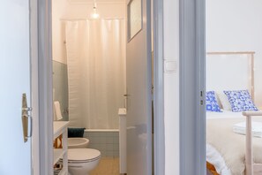 A bathroom with a toilet, sink, and shower curtain. - Renovated Sunny Apartment with Balcony, By TimeCooler (Lisbon)