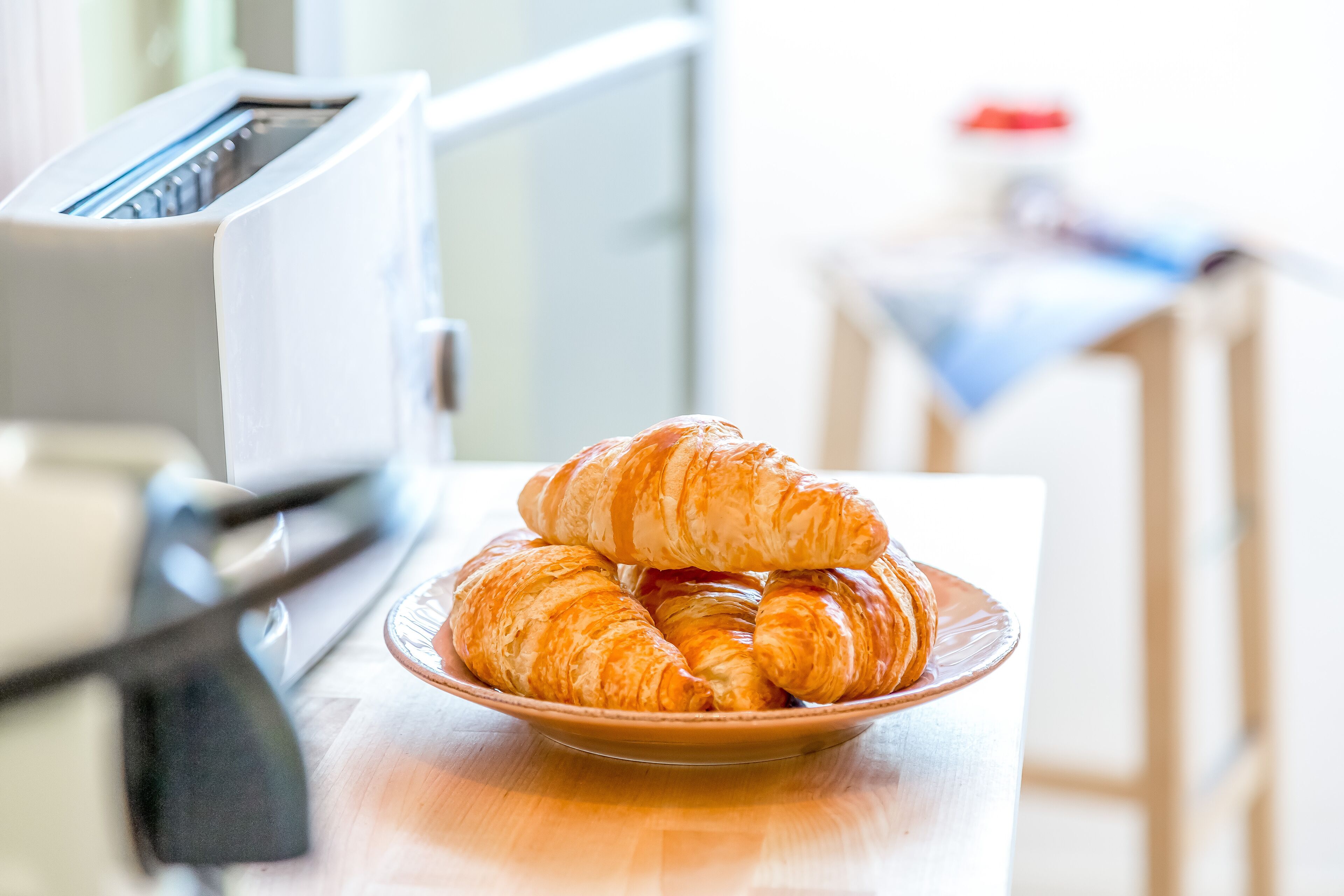 A plate of croissants on a table with a toaster in the background.