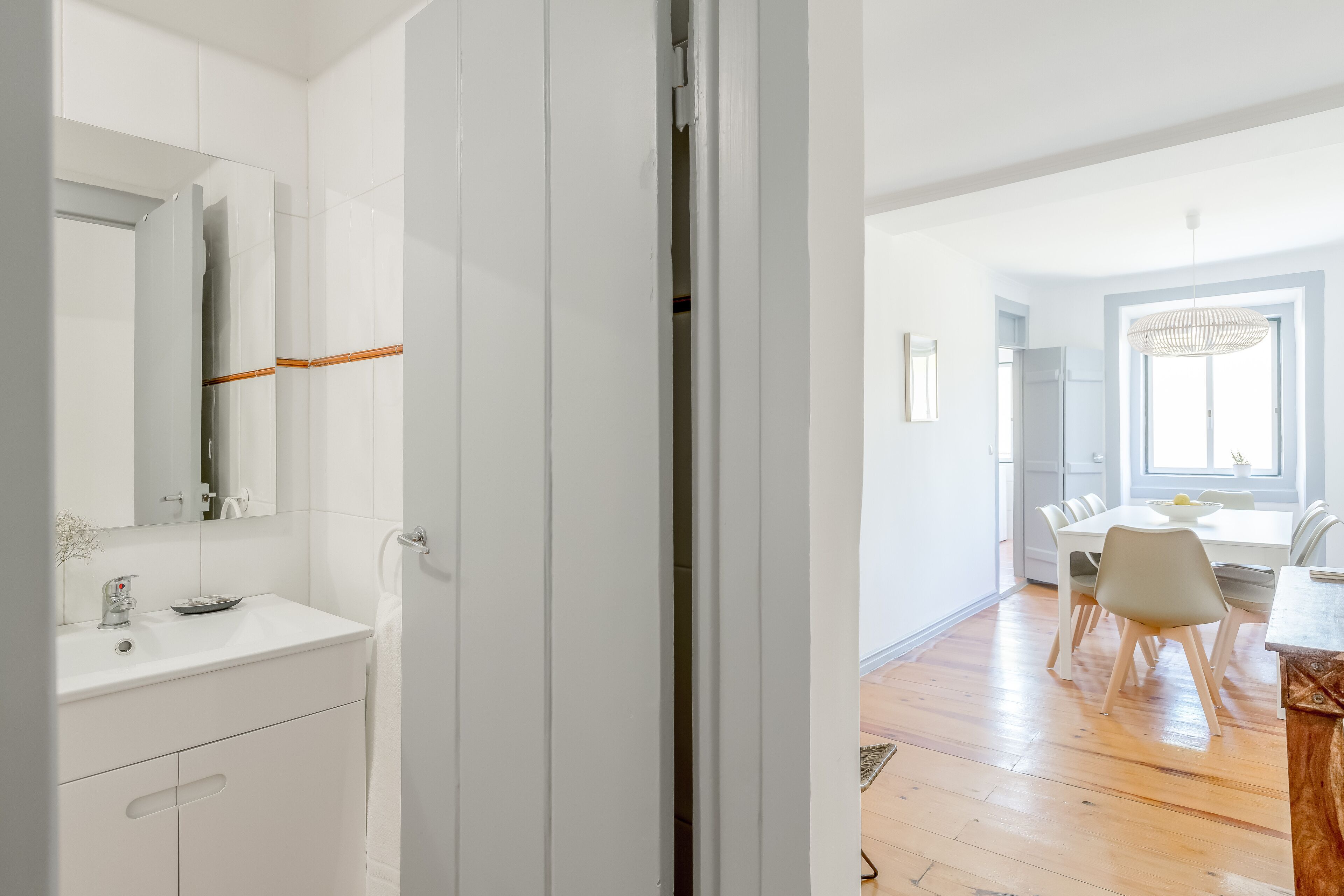 A modern bathroom with a white sink, mirror, and cabinets.