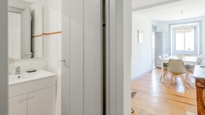 Ein modernes Badezimmer mit Waschbecken, Spiegel und Schränken, alles in Weiß.