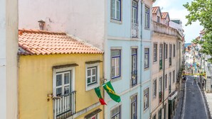 Eine enge Straße gesäumt von bunten Häusern, Balkonen und einer Flagge.