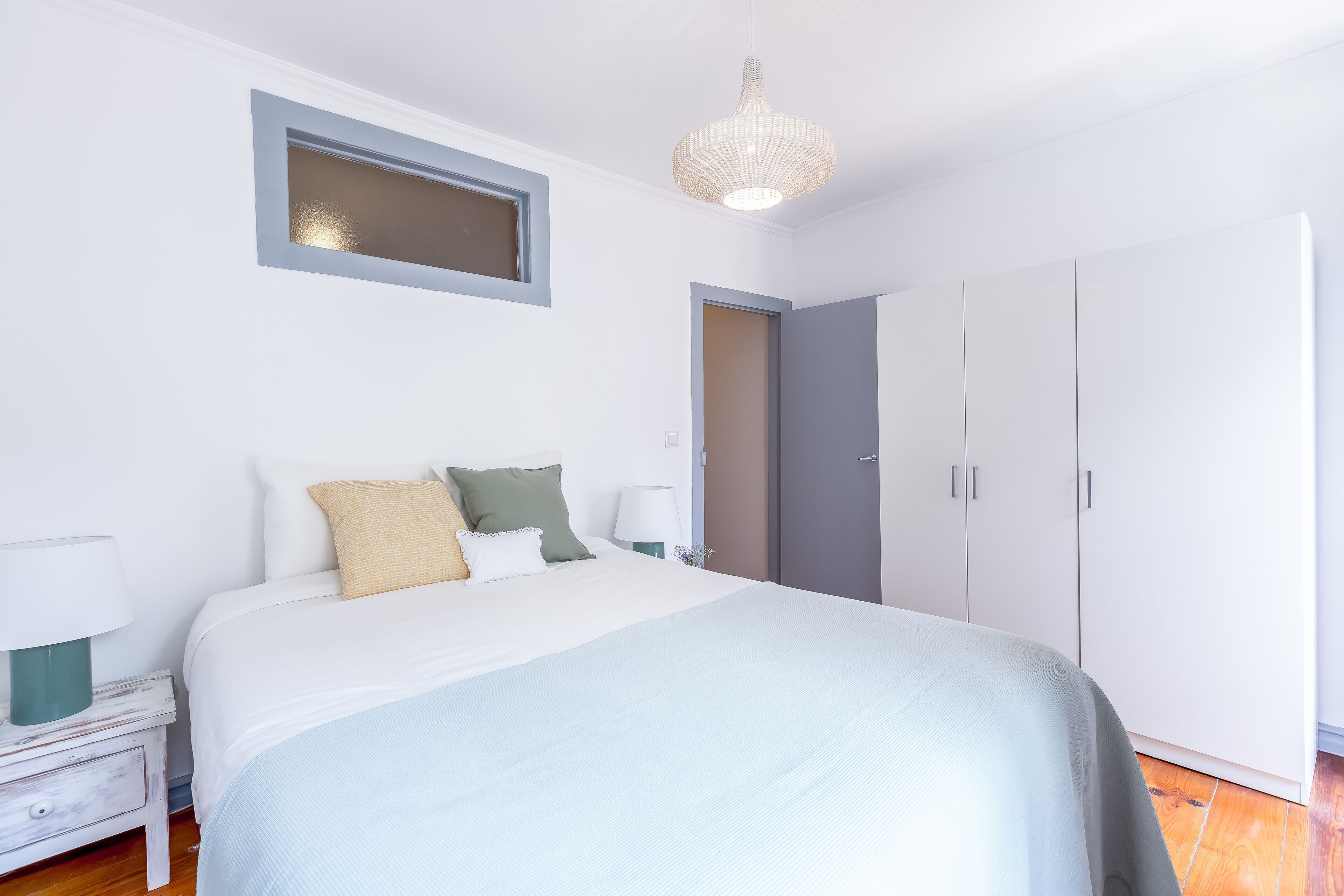 Un dormitorio con cama, mesitas de noche, armario y una lámpara colgante.