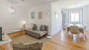 A modern living room with a sofa, a dining table, and a TV.