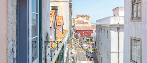 Un vicolo stretto con edifici su entrambi i lati, un balcone con ringhiera ben visibile e un carretto di un venditore ambulante in lontananza.