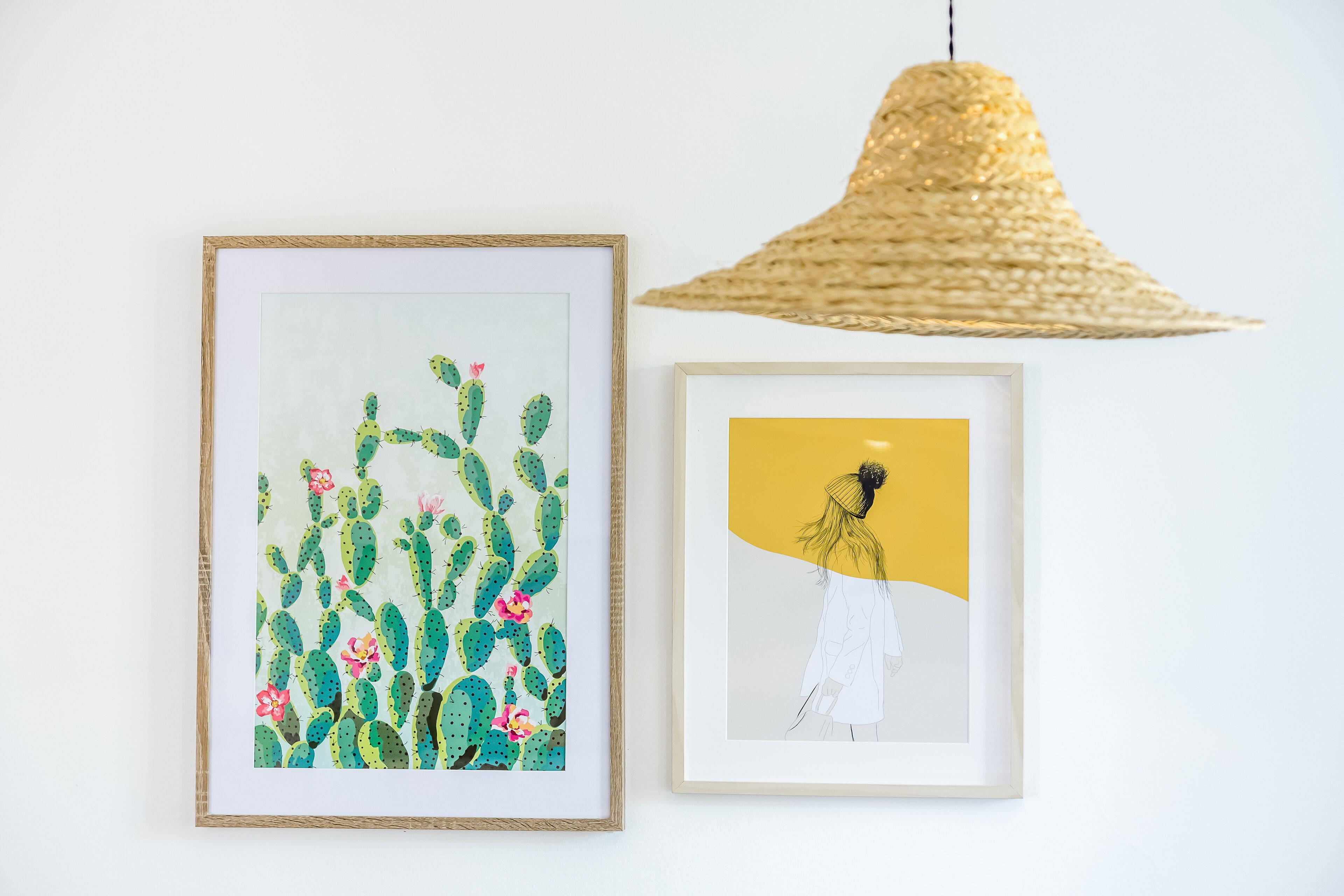 Deux œuvres d’art encadrées sont accrochées au mur : l’une représente des cactus en fleurs et l’autre, une figure sur un fond jaune.