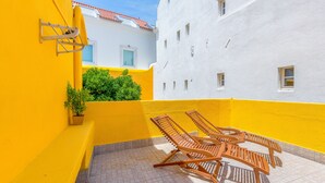 A yellow and white building with a tiled patio and wooden lounge chairs. - Alfama, Bright Spacious W/ Terrace Apartment, By TimeCooler (Lisbon)