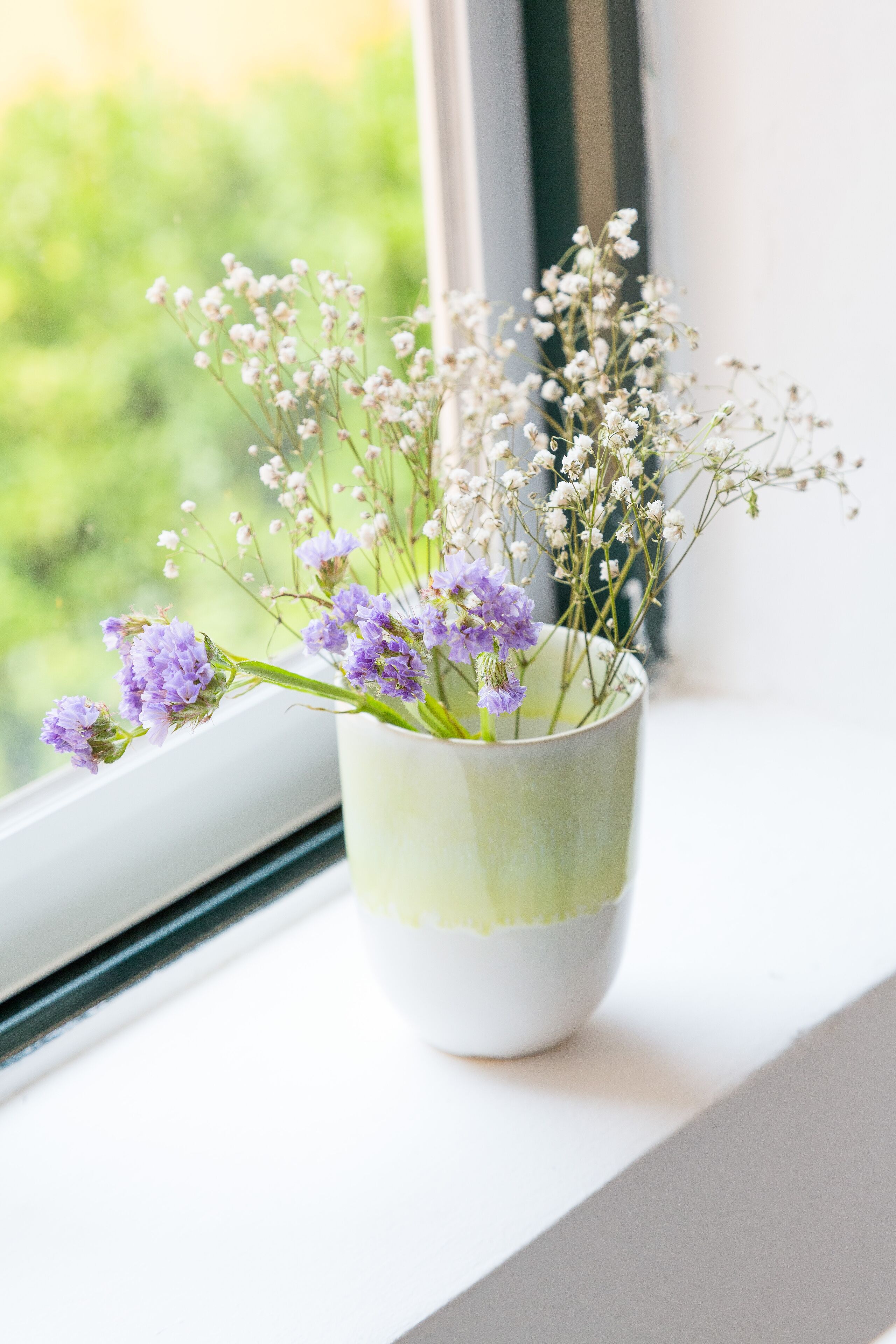 A window with a vase of flowers on a windowsill.