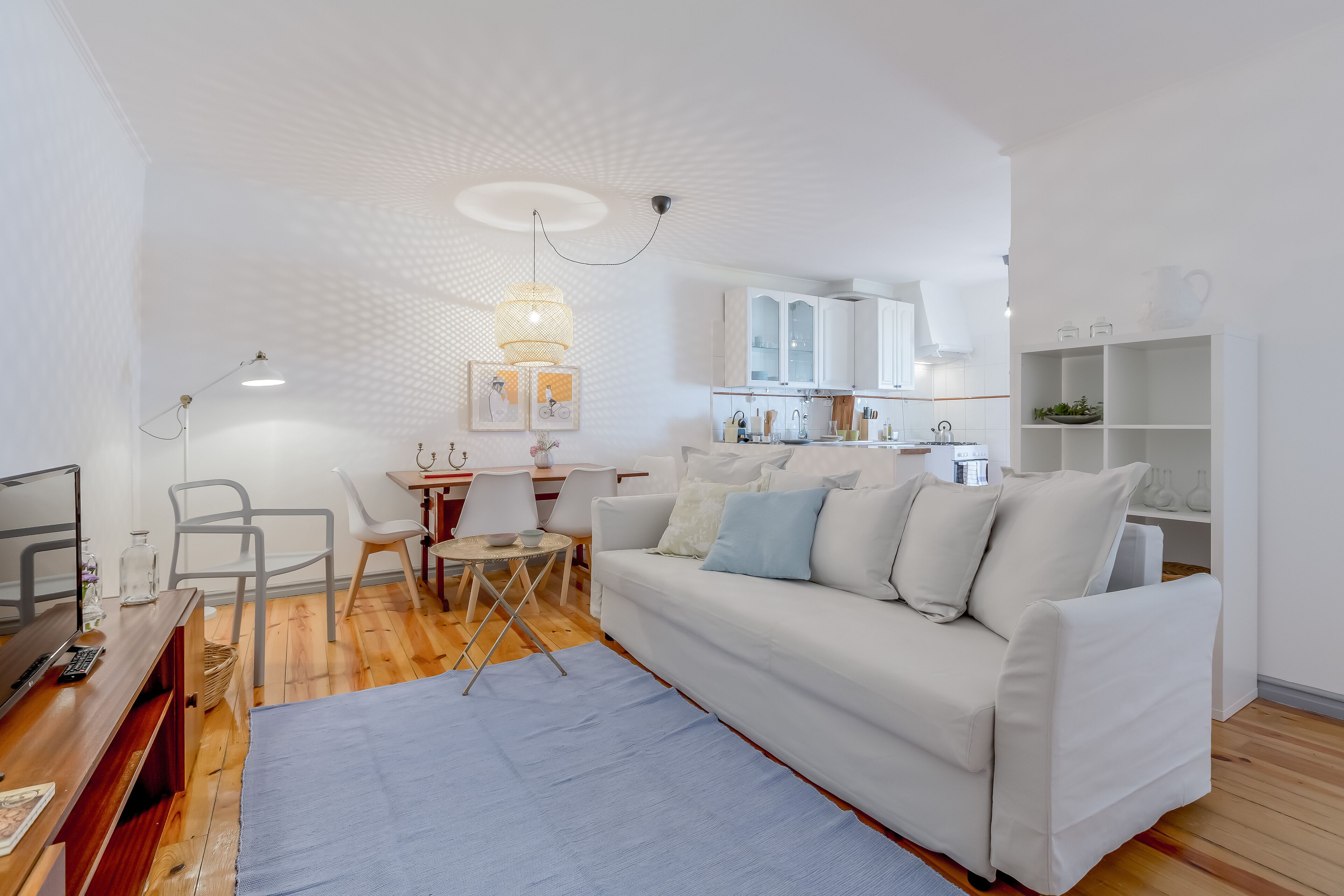A modern living room with a white sofa, a wooden coffee table, and a TV on a wooden stand.
