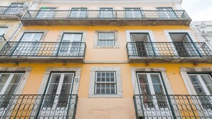 Un edificio de varios pisos con balcones, ventanas y fachada amarilla.
