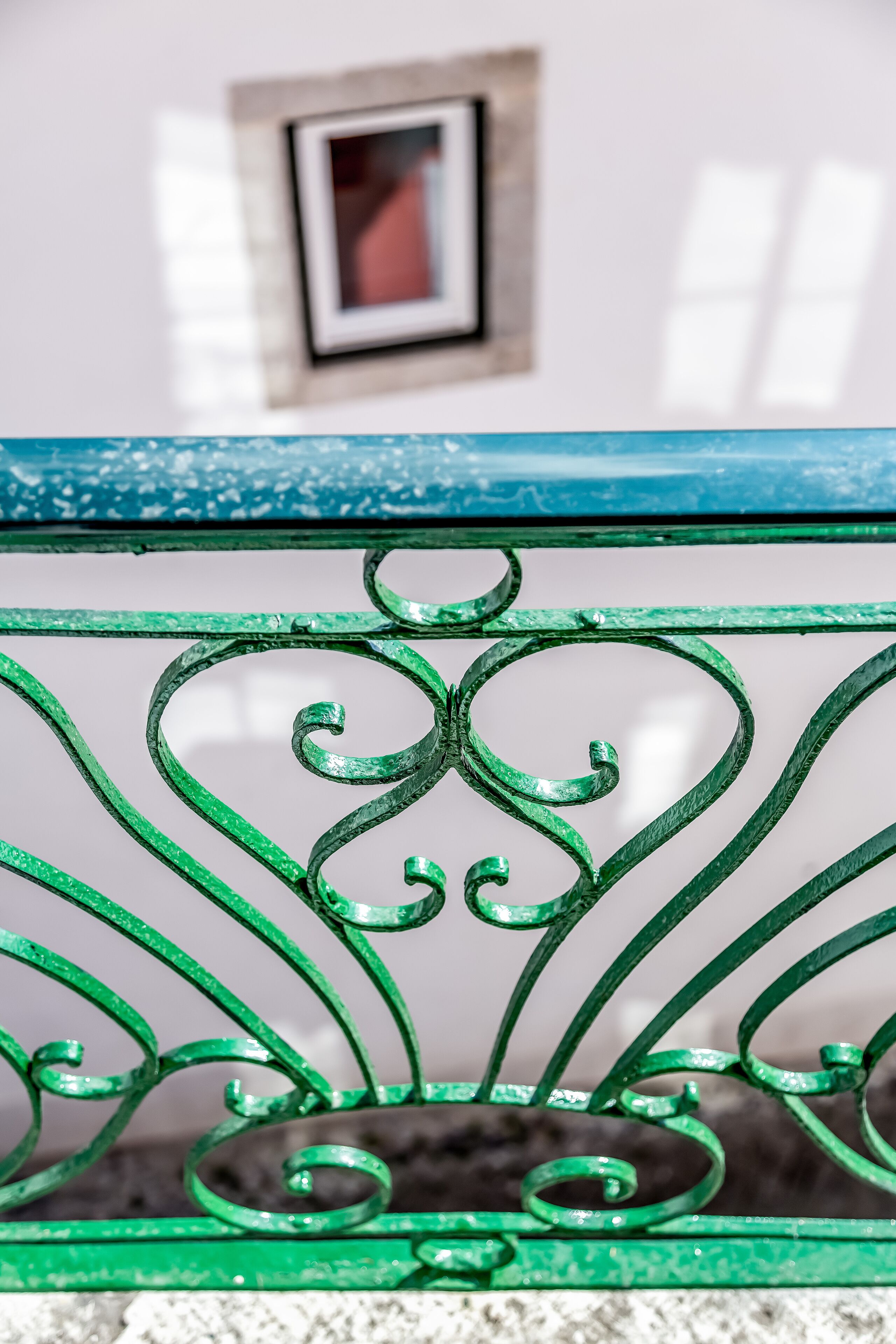 A close-up of a green metal railing with ornate designs.