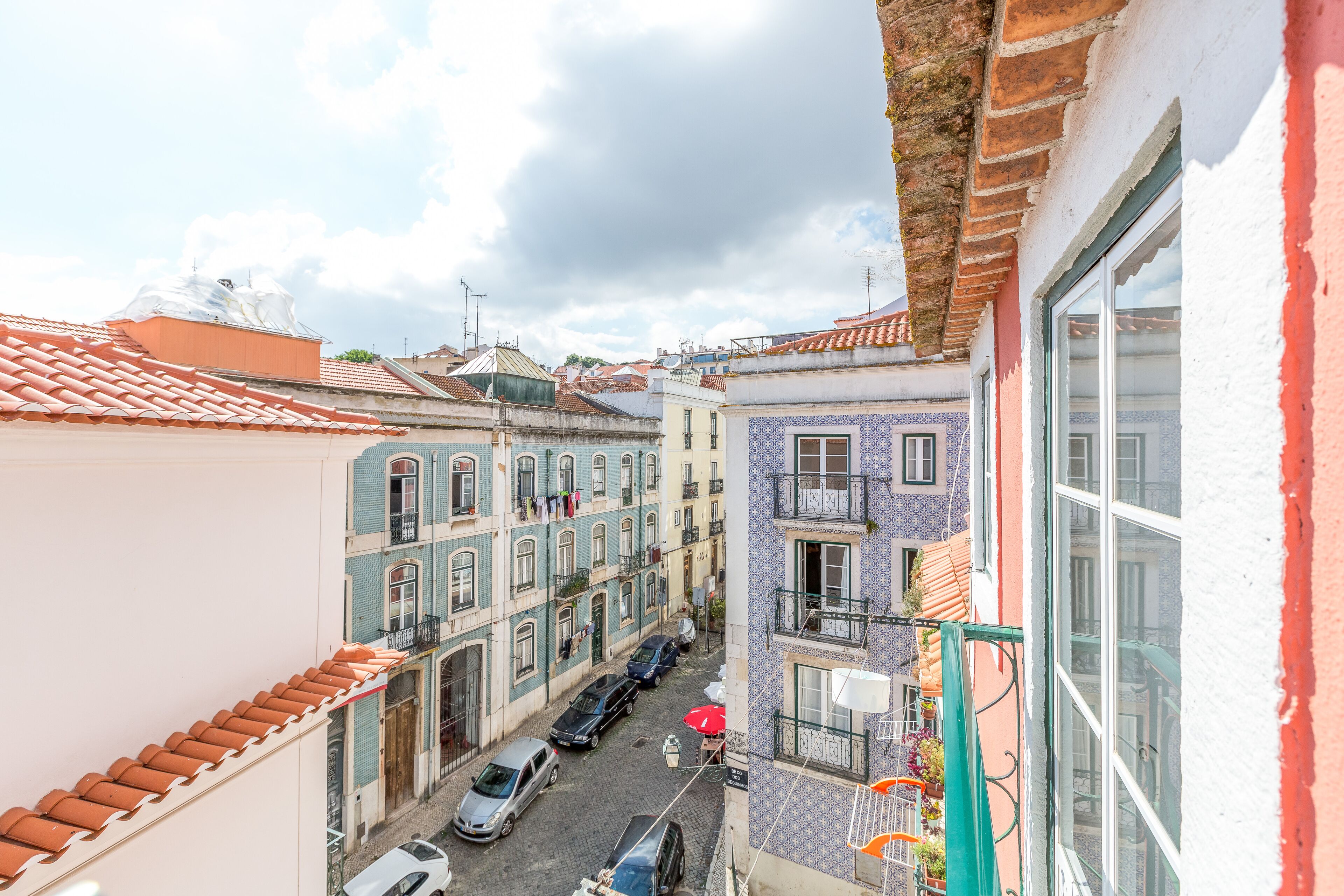 Uma rua estreita com edifícios em ambos os lados, com varandas e calçada de pedra.