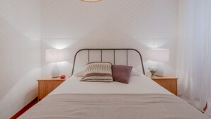 A neatly arranged bedroom with a bed, two bedside tables, and a hanging light fixture. - Typical Alfama Apartment, By TimeCooler (Lisbon)