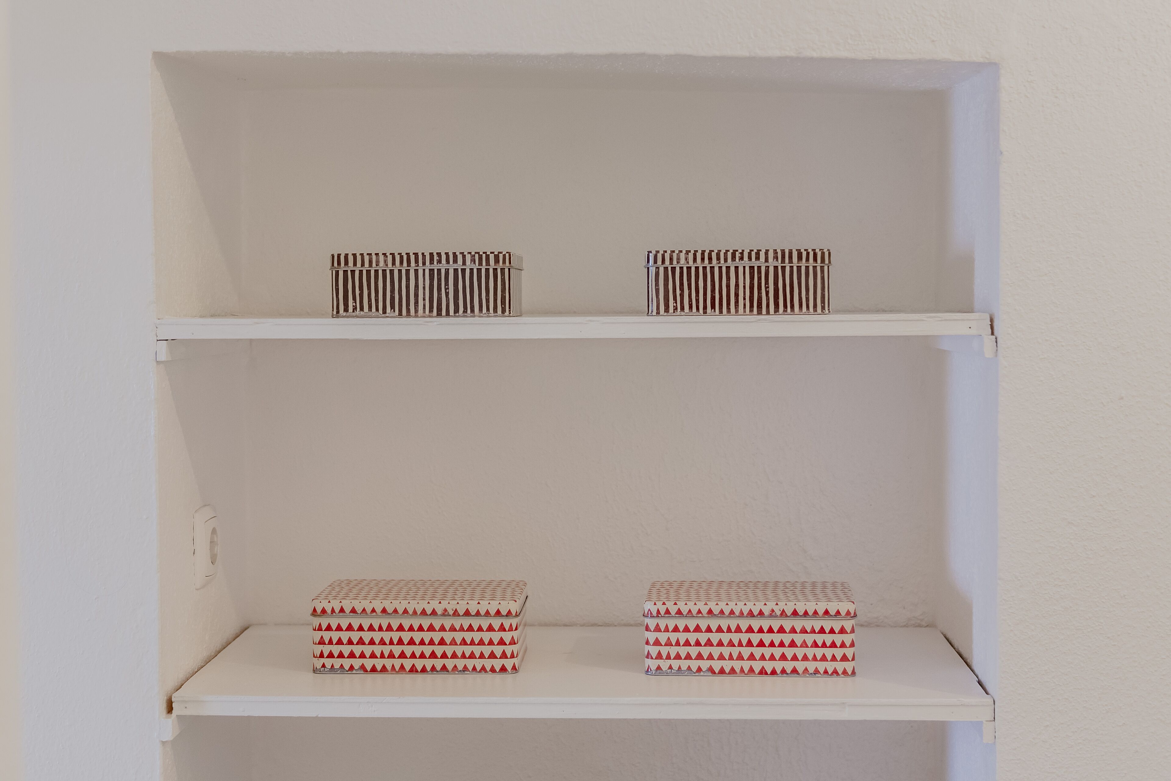 A white shelf with two boxes on the top and two boxes on the bottom.