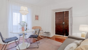 A modern living room with a round dining table, two black chairs, a wicker chair, a small side table, and a sofa. - Typical Alfama Apartment, By TimeCooler (Lisbon)