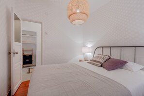A neatly arranged bedroom with a bed, bedside table, lamp, and open wardrobe. - Typical Alfama Apartment, By TimeCooler (Lisbon)