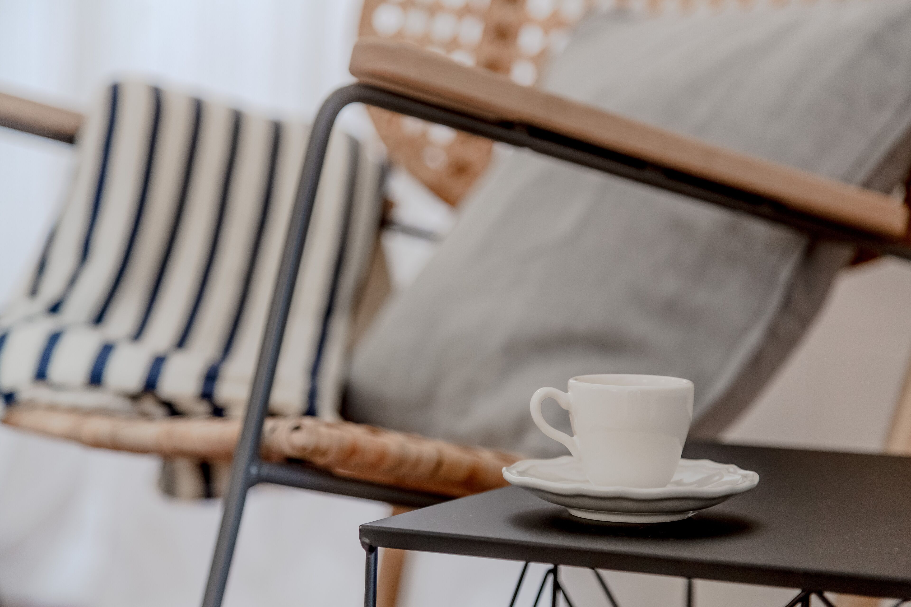Una taza blanca sobre un platito, sobre una pequeña mesa.