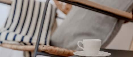 Una taza blanca sobre un platito, sobre una pequeña mesa.