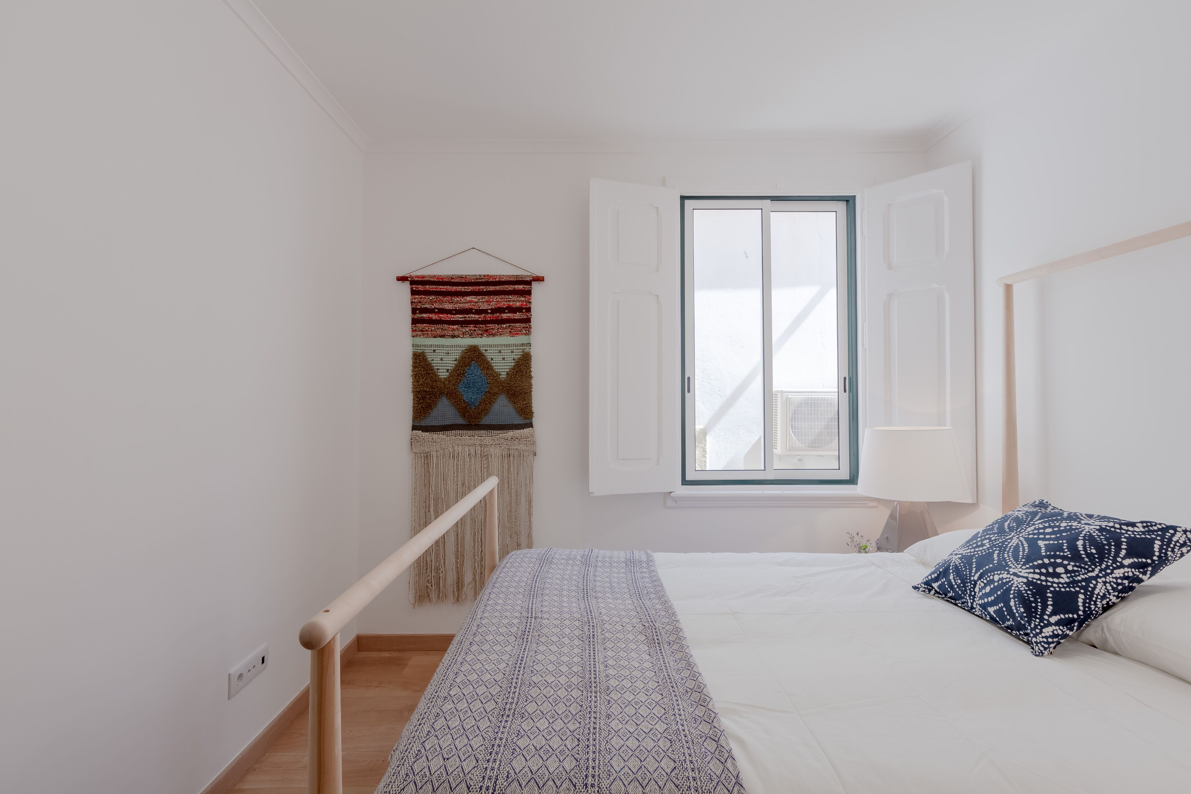 Une chambre à coucher avec un lit, une fenêtre, une décoration murale et une rambarde en bois.
