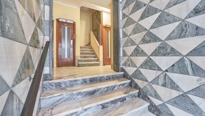 A staircase with marble steps leading to a landing with a wooden door and a metal gate. - Light Apartment W/ Balcony Apartment by TimeCooler (Lisbon)