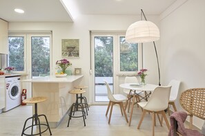 A modern kitchen with a dining area, large windows, and a hanging light fixture. - Light Apartment W/ Balcony Apartment by TimeCooler (Lisbon)