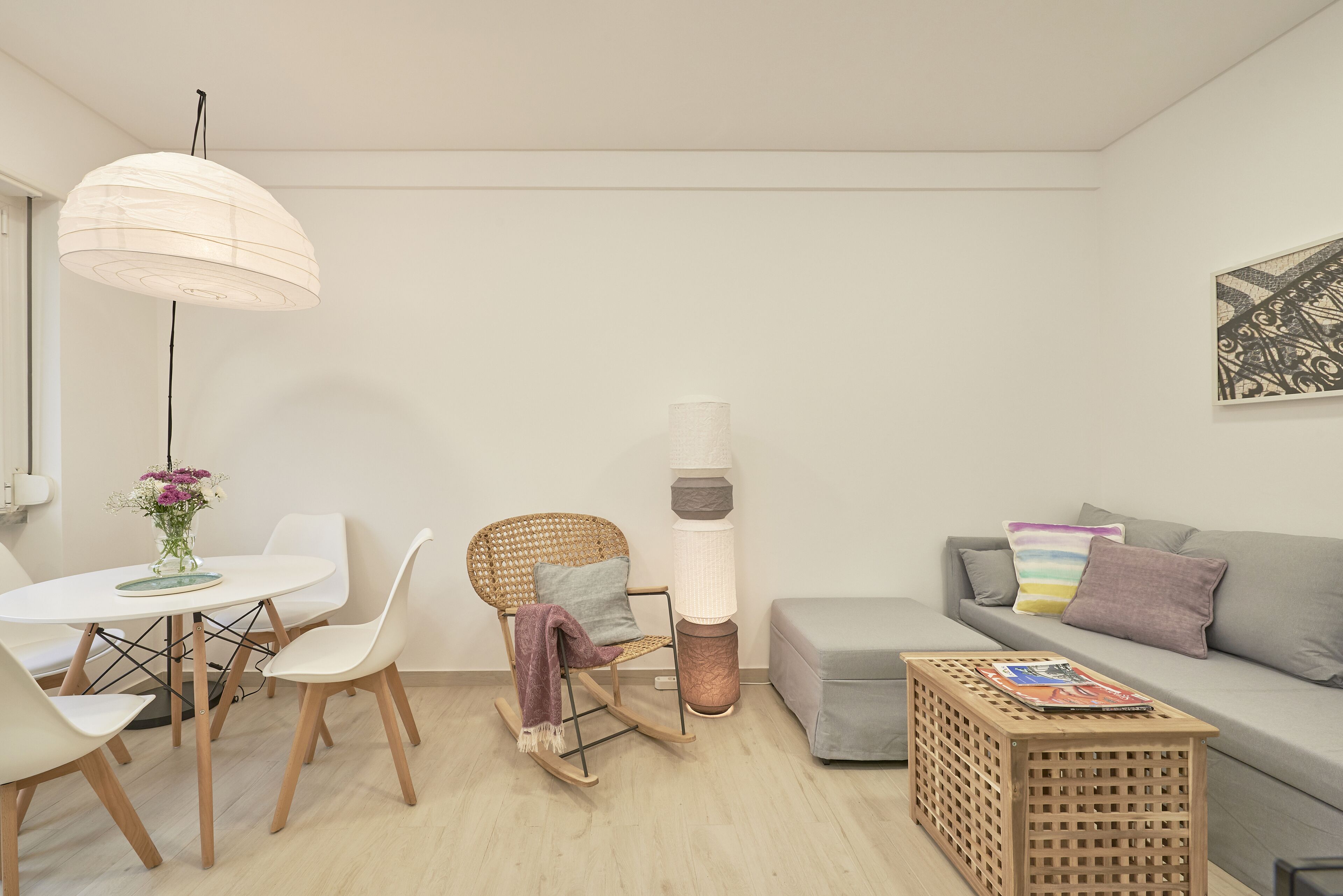A modern living room with a dining table, a rocking chair, a sofa, and a coffee table.