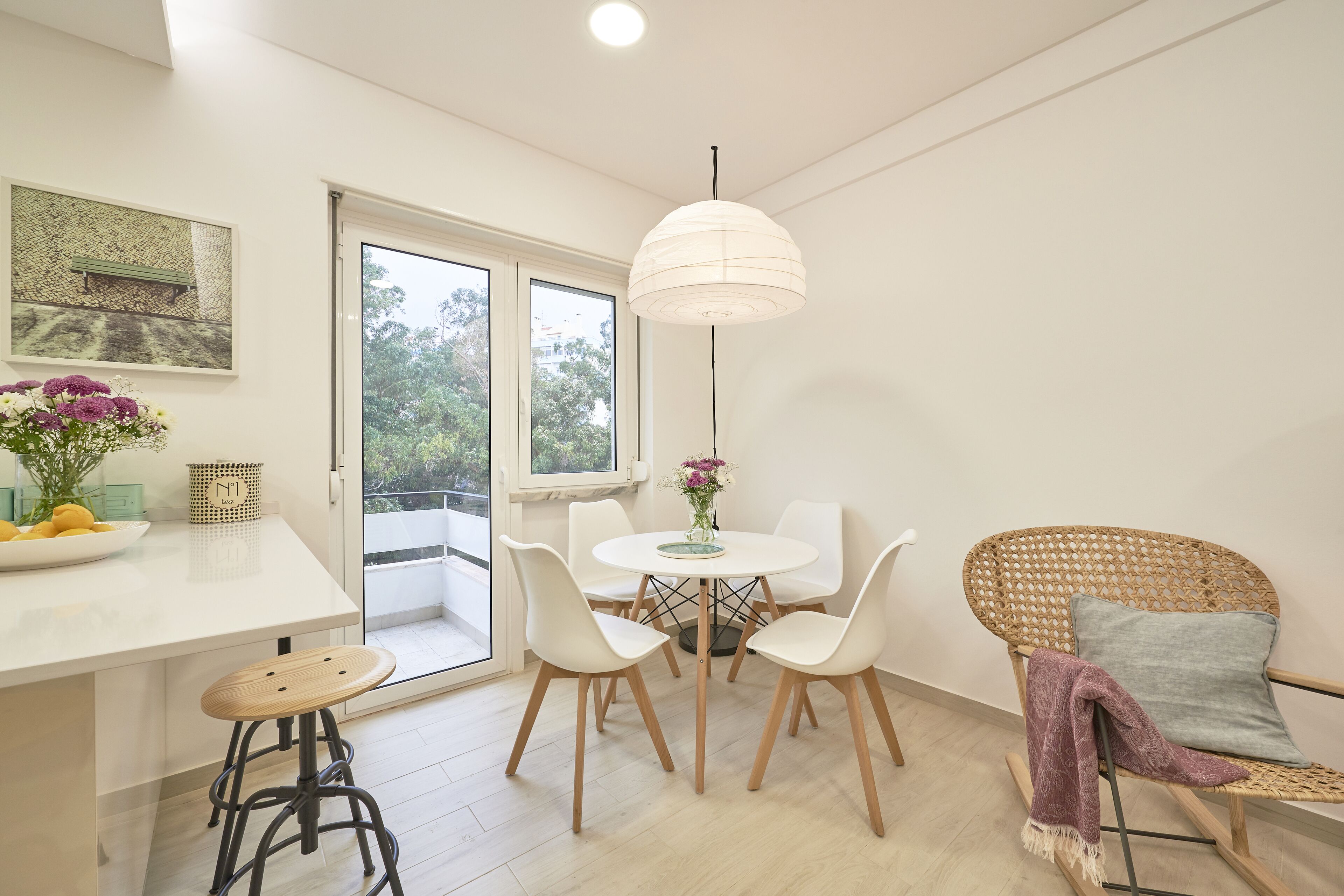 Une cuisine moderne avec un coin repas, comprenant une table blanche, des chaises et un luminaire suspendu.