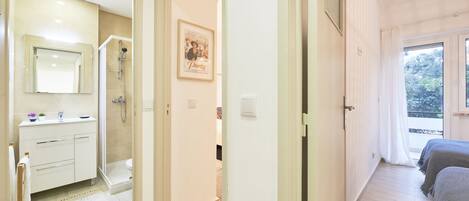 Hotelkamer met een badkamer, douche, bed en raam met uitzicht op bomen.