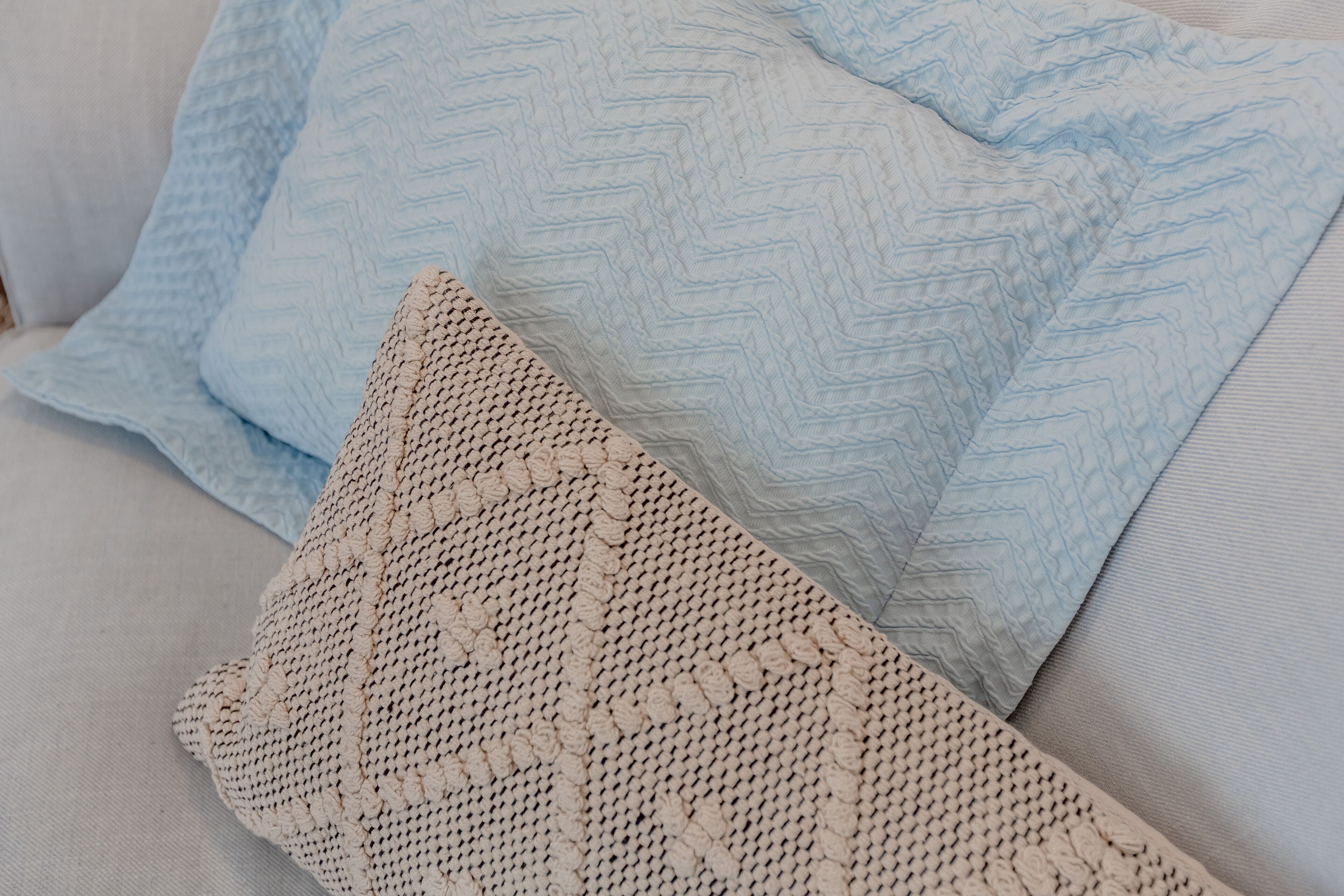 A close-up of a sofa with patterned cushions and a textured throw blanket.