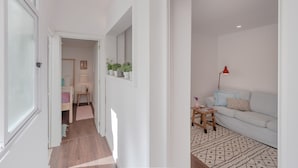 A hallway leading to a living area with a sofa, a small table, and a lamp. - Sunny Apartment with Patio, By TimeCooler (Lisbon)