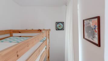 A bunk bed with a blue and white striped pillow, a framed picture of a car on the wall, and a small framed picture above the bed.