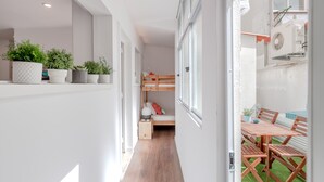 A narrow hallway with a bunk bed, a small table, and potted plants. - Sunny Apartment with Patio, By TimeCooler (Lisbon)