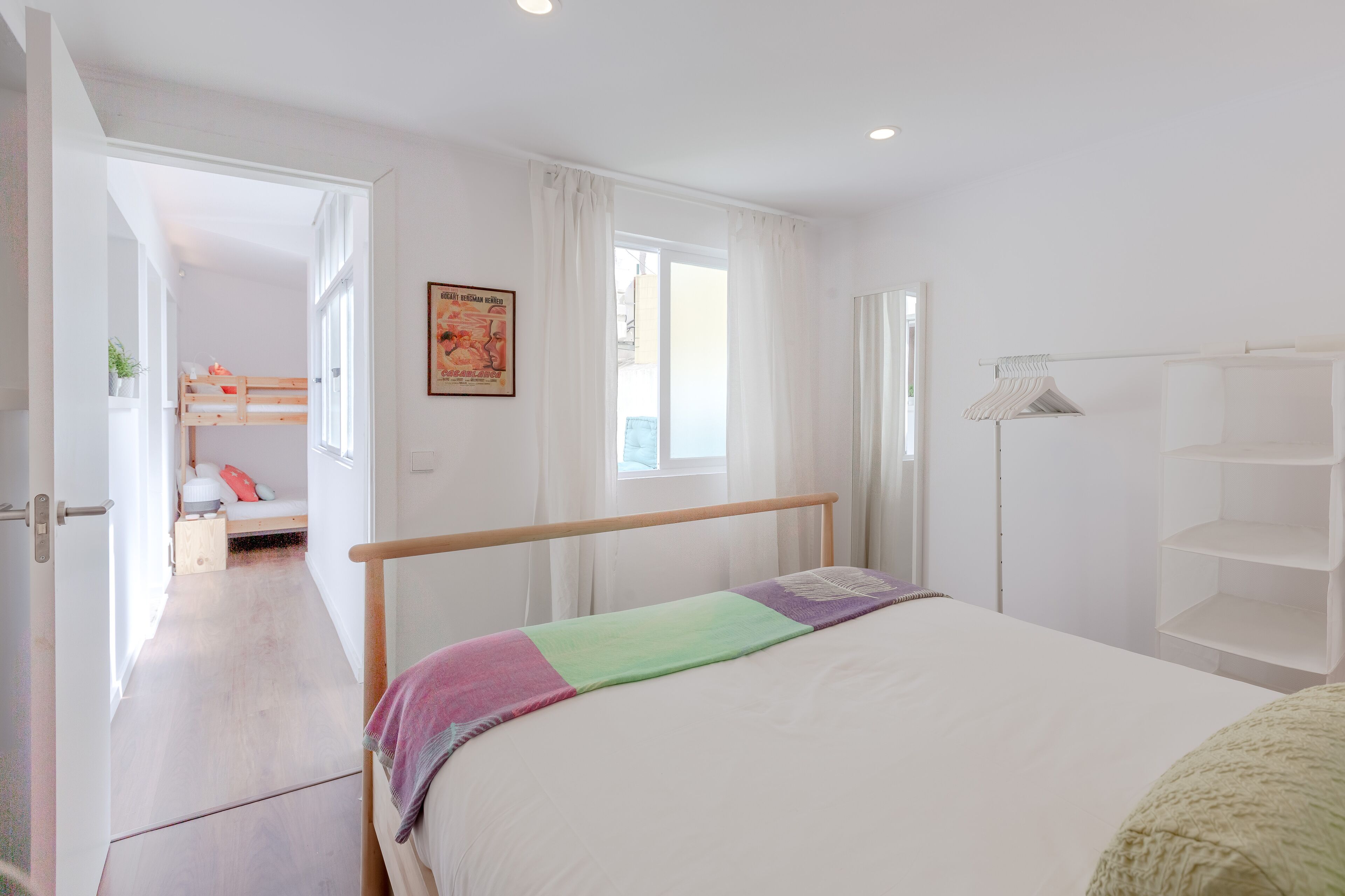 Un dormitorio con cama, armario, mesita de noche y ventana.
