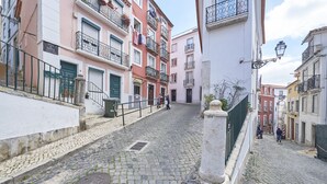 A cobblestone street lined with multi-story buildings, some with balconies and flower boxes. - Alfama Light-Filled Apartment, By TimeCooler (Lisbon)