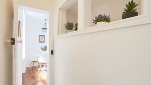 A narrow hallway with wooden flooring and white walls, leading to a dining area with a table and chairs. - Alfama Light-Filled Apartment, By TimeCooler (Lisbon)