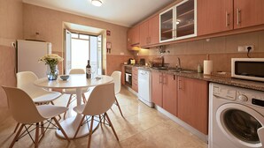 Una cocina moderna con comedor, armarios de madera, microondas integrado y lavadora.