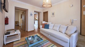 Una sala de estar con un sofá blanco, una mesa de centro y una lámpara colgante.